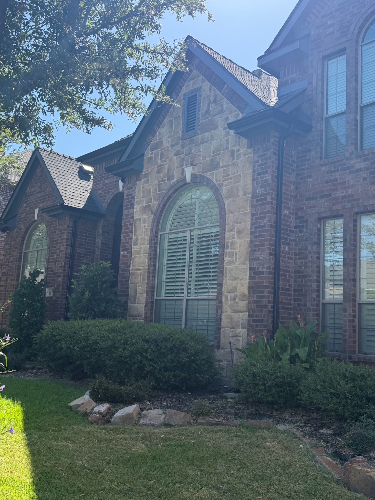 Replacement arched window with plantation shutters set in a stone surround on a McKinney, TX home